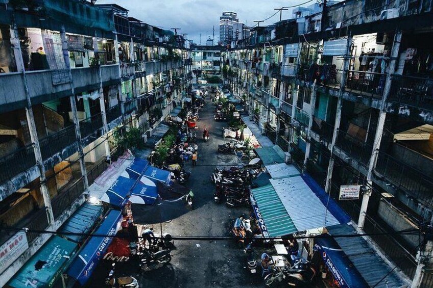 A densely packed urban market with multiple levels of buildings, market stalls, and a variety of goods. 4