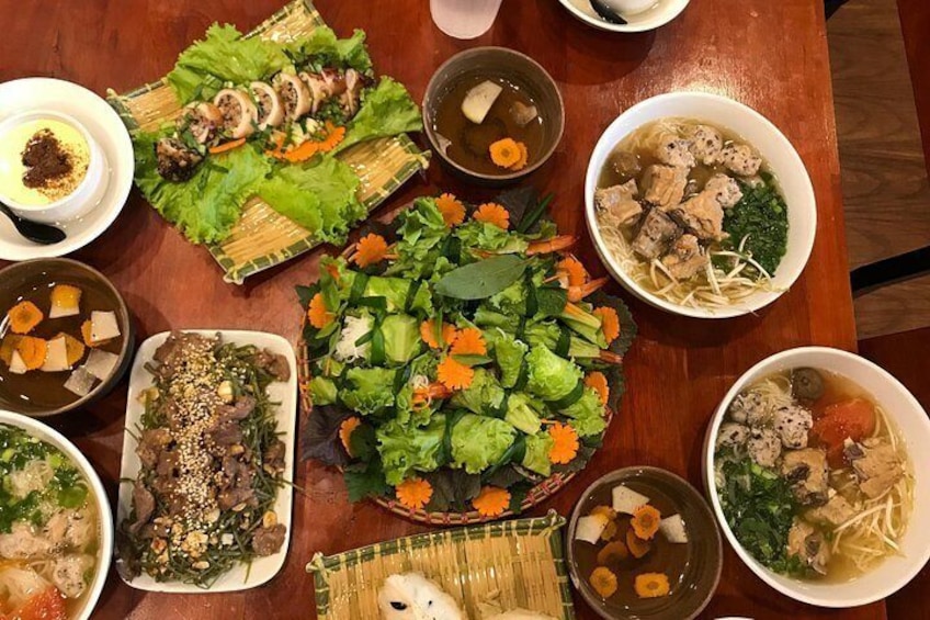 Une variété de plats, notamment une salade, une soupe et des plats de viande, sont disposés sur une table en bois. 4