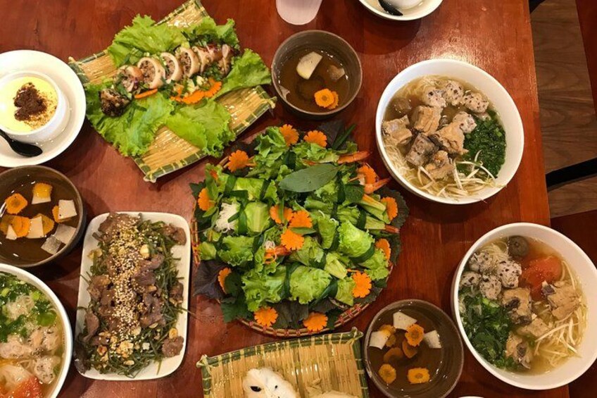 Variedad de platos, incluyendo ensalada, sopa y guisos de carne, sobre una mesa de madera. 2