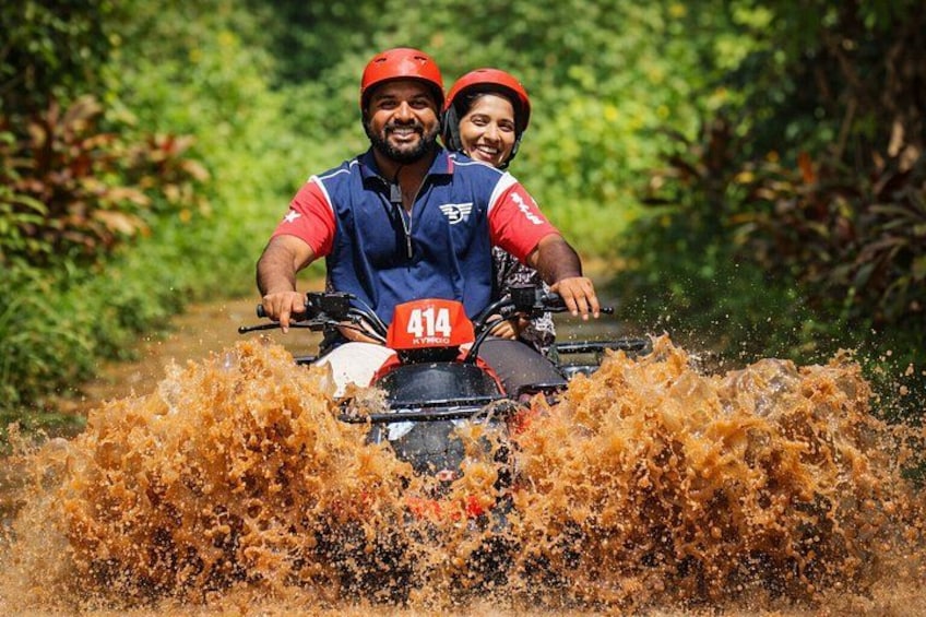 Two people on an ATV in a muddy area. 1