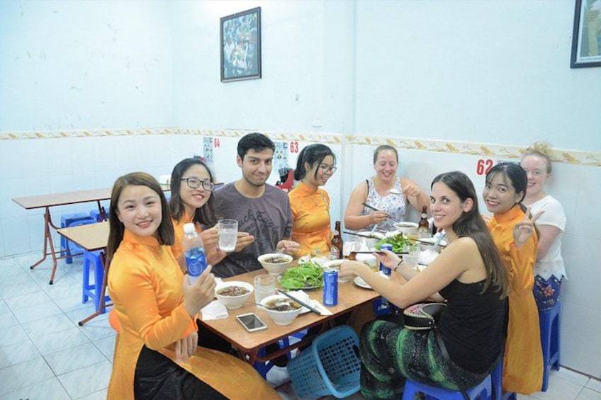 A group of people sitting around a table in a room with numbered lockers on the wall. 2