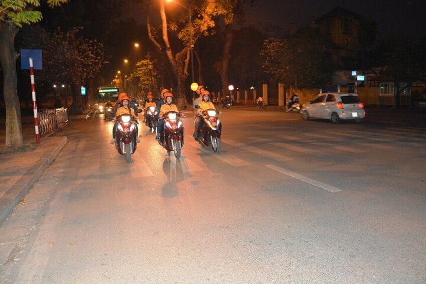 Un grupo de motociclistas circulando por una calle urbana de noche. 3