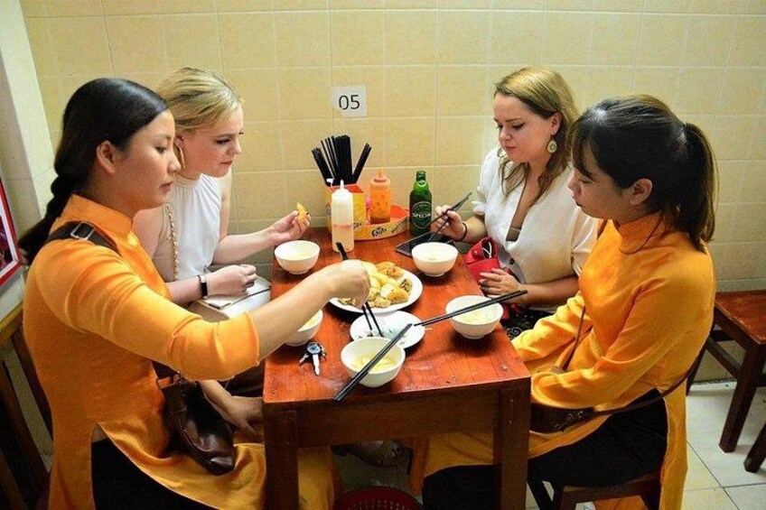 Un grupo de personas sentadas alrededor de una mesa con cuencos y palillos, presumiblemente cenando. 2