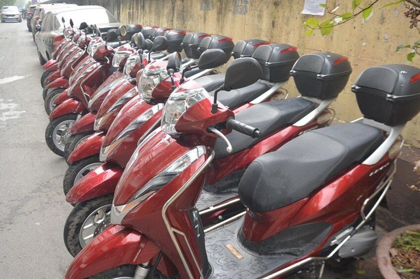 A row of red scooters parked along a street. 2