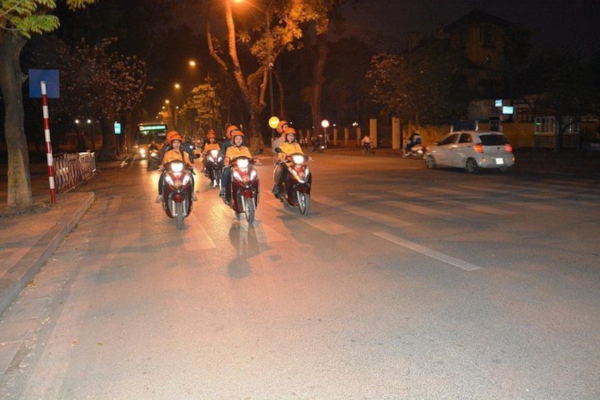 A group of motorcyclists riding on a city street at night. 2