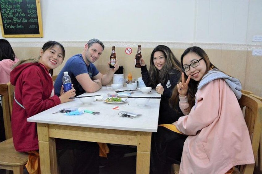 Un grupo de personas sentadas en una mesa con comida y bebidas, en un ambiente de restaurante informal. 5