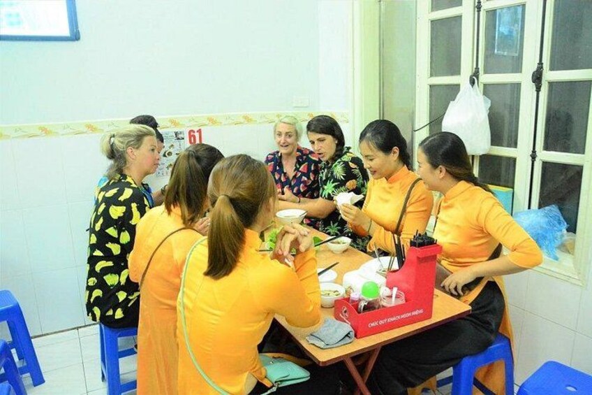 Un grupo de personas sentadas alrededor de una mesa en una habitación con ventana y puerta. 2