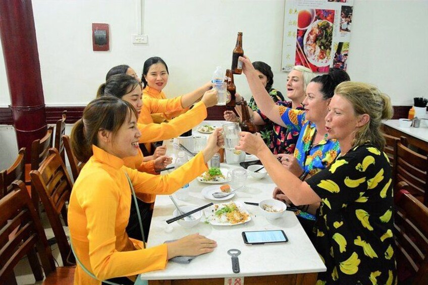 Un grupo de personas alrededor de una mesa, brindando con botellas. 4