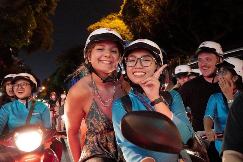 Een groep mensen op scooters, met helmen, 's nachts. 4