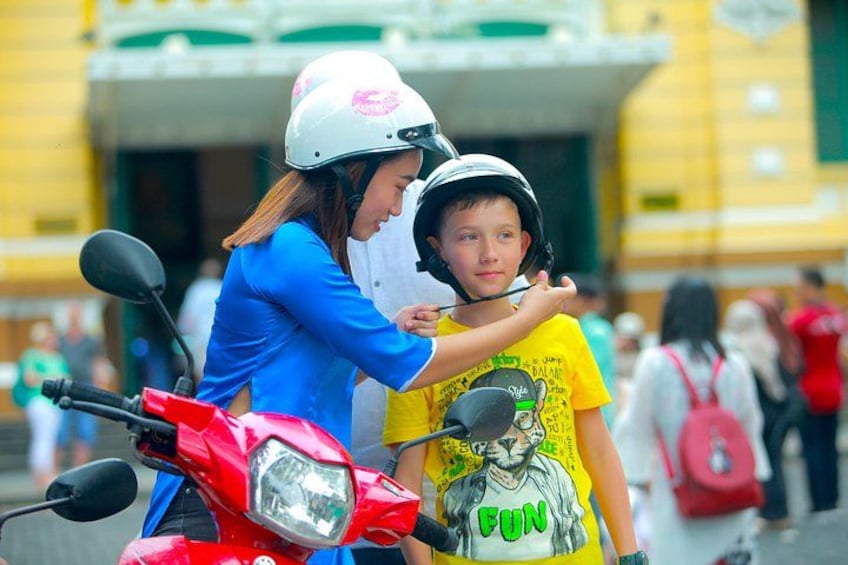 Una scooter roja con un conductor con casco y un niño con camiseta amarilla. 3