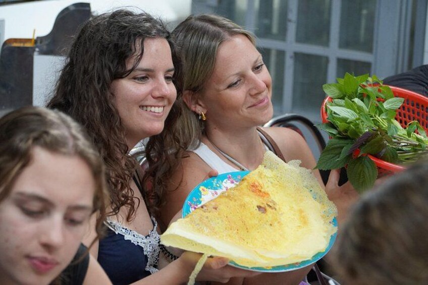 Eine Person hält ein Crêpe, nebenan ein Korb mit grünen Blättern. 4