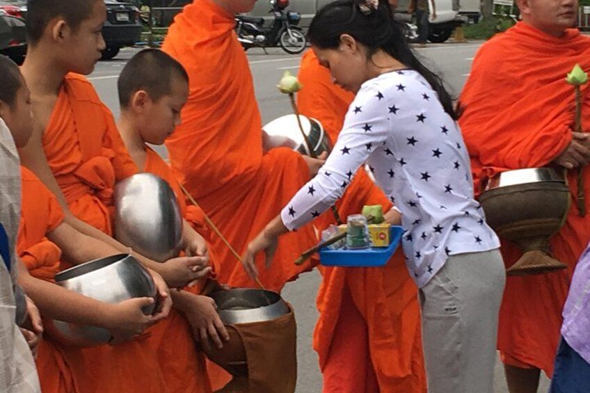 Monks in orange robes performing a ritual with offerings. 3