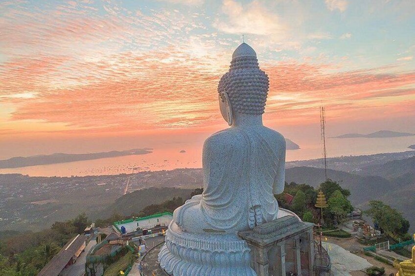 A large seated Buddha statue overlooking a coastal landscape during sunset. 3