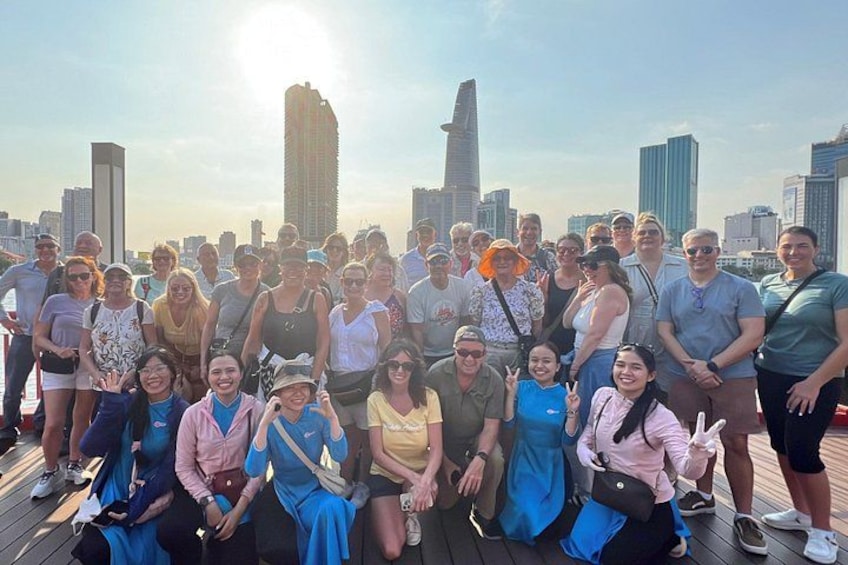 A group of people posing on a wooden deck with a city skyline in the background. 3