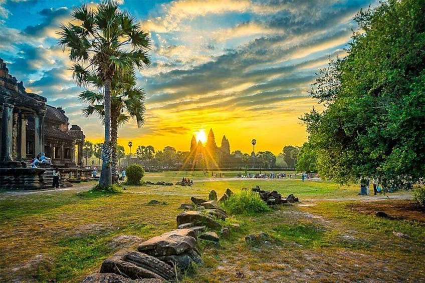 Un coucher de soleil sur un site historique, avec un temple, des palmiers et un sentier pavé de pierres. 2