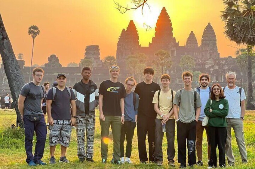 En grupp människor som står framför tempelkomplexet Angkor Wat under solnedgången. 5