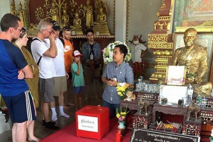 Un grupo de personas en un templo con estatuas doradas y ofrendas. 3