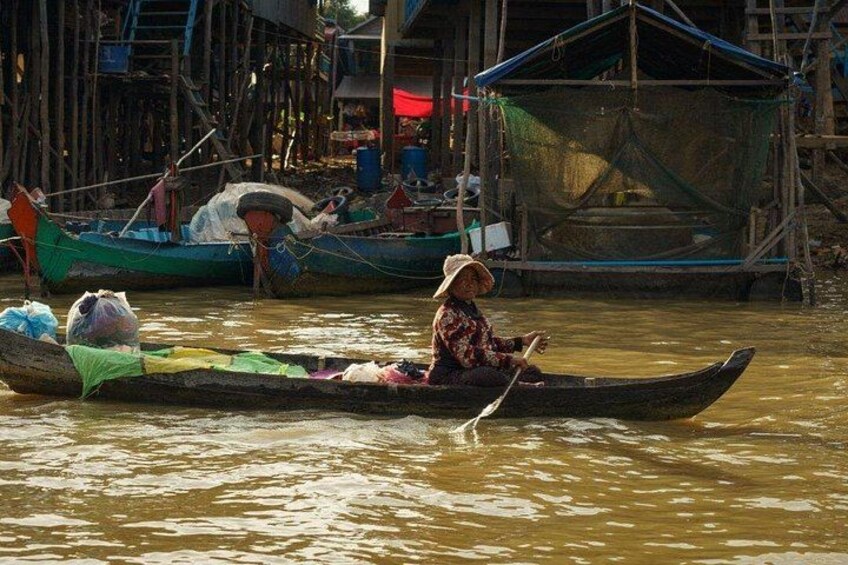 A person in a boat on a river, surrounded by wooden structures and other boats. 5