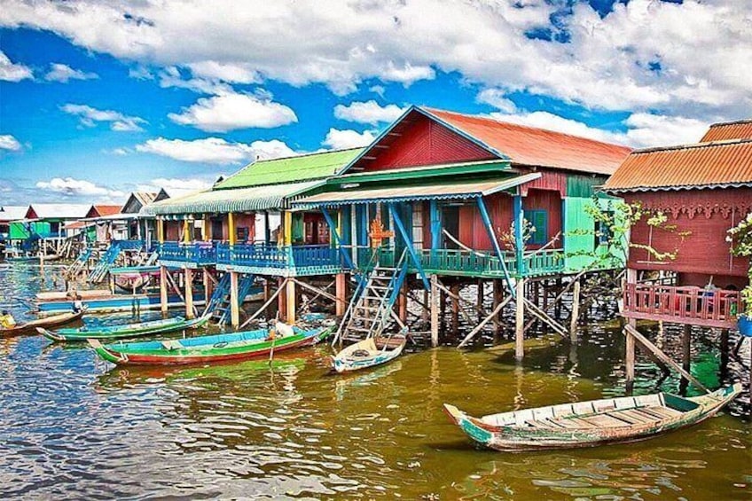 A row of colorful stilt houses over water, boats, and a clear blue sky. 3