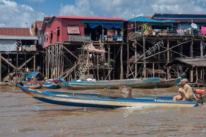 A river with boats, wooden structures, and a person sitting on a boat. 2
