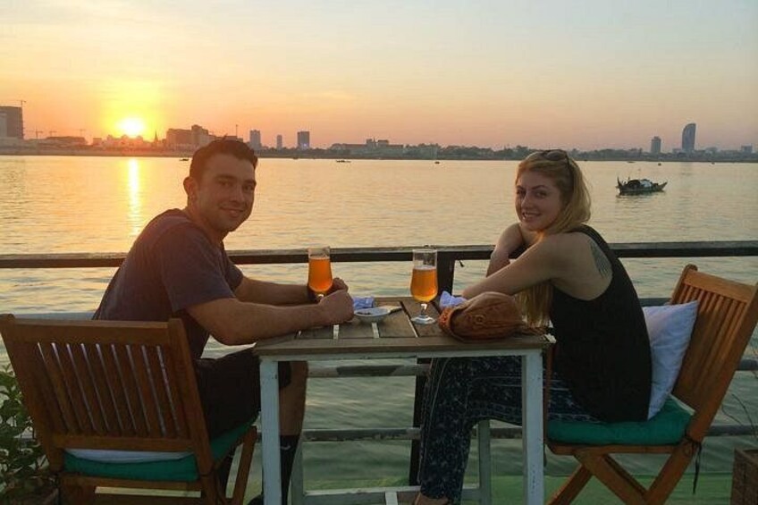 Dos personas sentadas a una mesa frente al agua al atardecer. 4