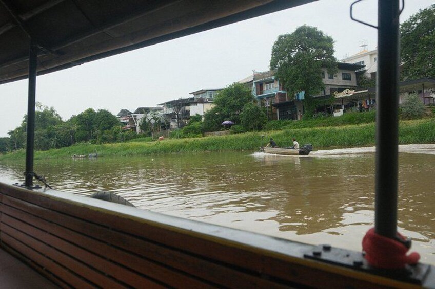 A river with a boat, wooden benches, and buildings in the background. 4