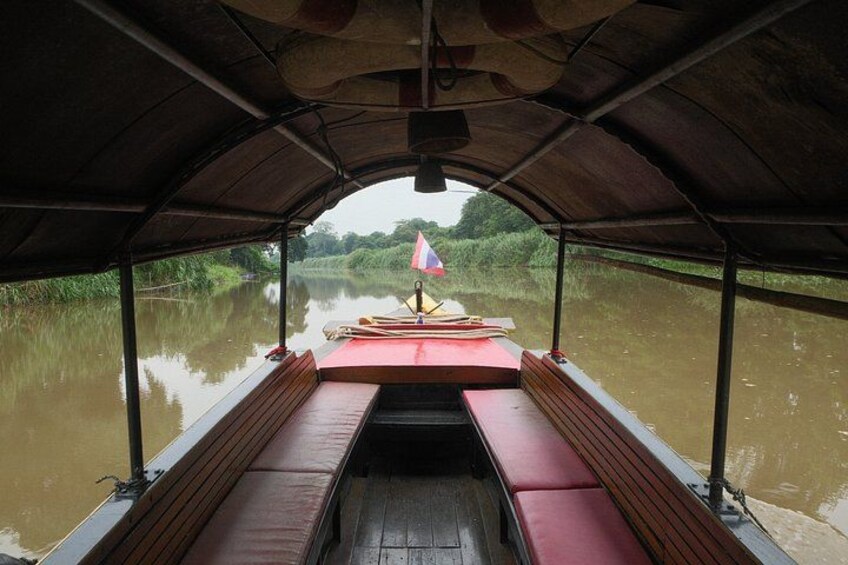 A covered boat with benches and a table, surrounded by calm water and greenery. 2