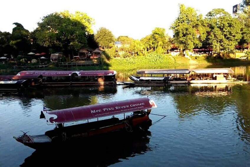 A river with boats, trees, and a building in the background. 1