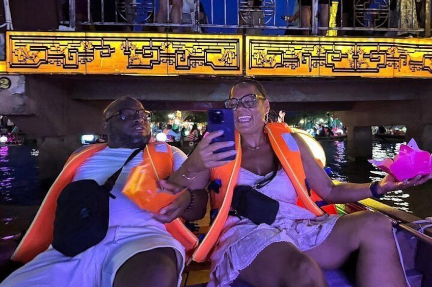 Two people on a boat, one wearing an orange life jacket, taking a selfie. 4