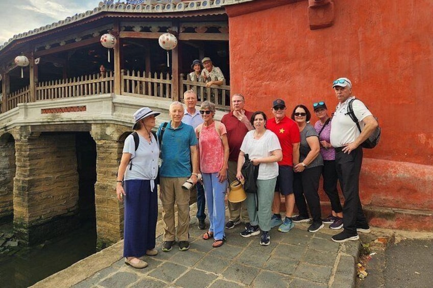 A group of people standing in front of a traditional building with a stone bridge. 3