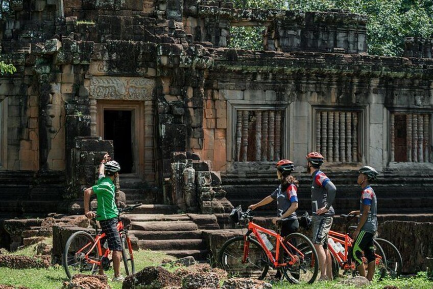 A group of cyclists near an ancient temple with stone steps and intricate carvings. 4