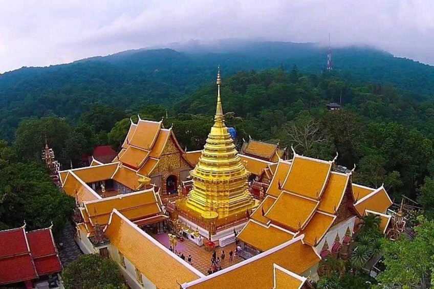 A golden pagoda surrounded by lush green hills. 1