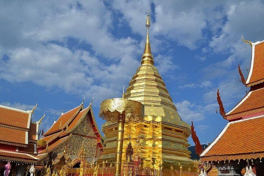 Et gyldent stupa omgivet af traditionel thai arkitektur. 2