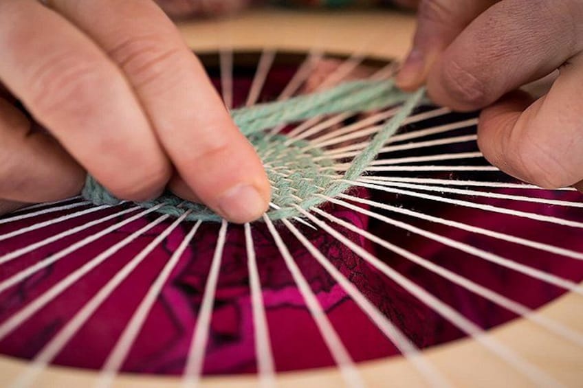 Hands weaving a fabric with a wooden frame. 2