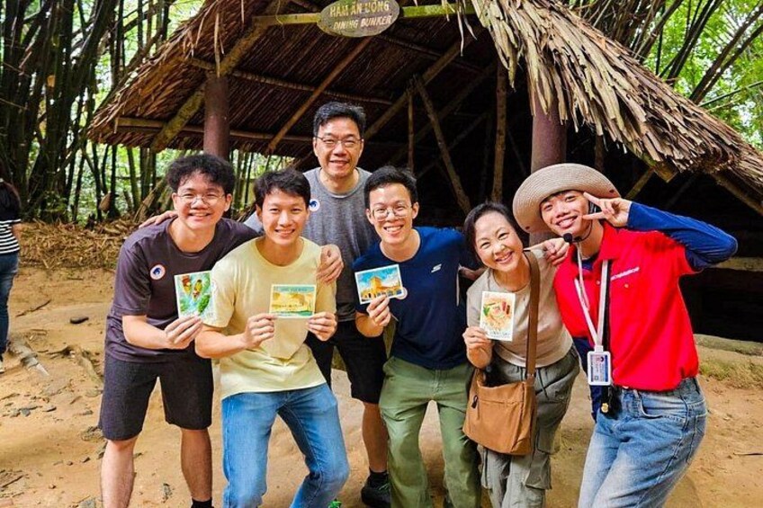 A group of people standing in front of a bamboo structure with a thatched roof. 2