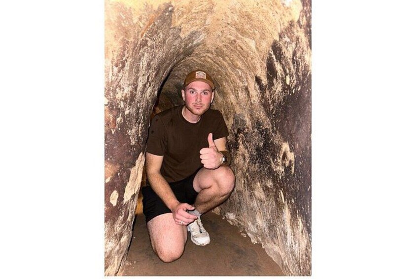 A person crouching inside a cave with rough walls. 5