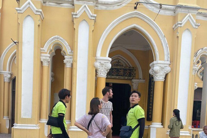 Un groupe de personnes se tient devant un bâtiment jaune orné de colonnes et d’arcades blanches. 5