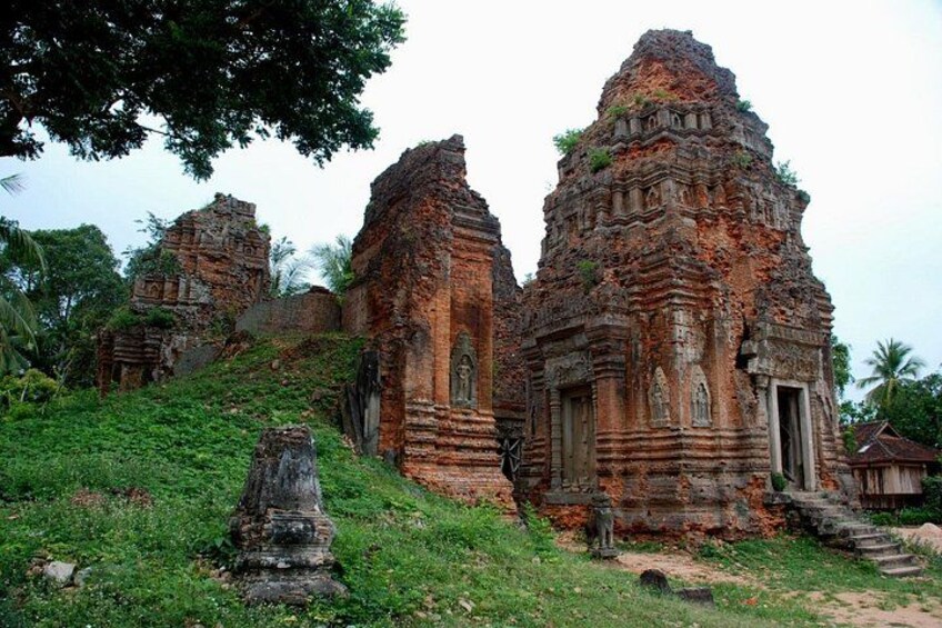 Ancient brick temple ruins with intricate carvings, surrounded by lush greenery and a clear sky. 2