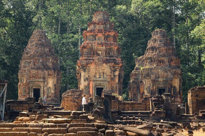 Ancient stone structures with intricate carvings, surrounded by dense forest. 1