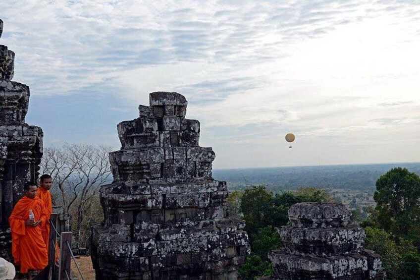 Ancient stone structures, a person in orange robes, and a hot air balloon in the distance. 3