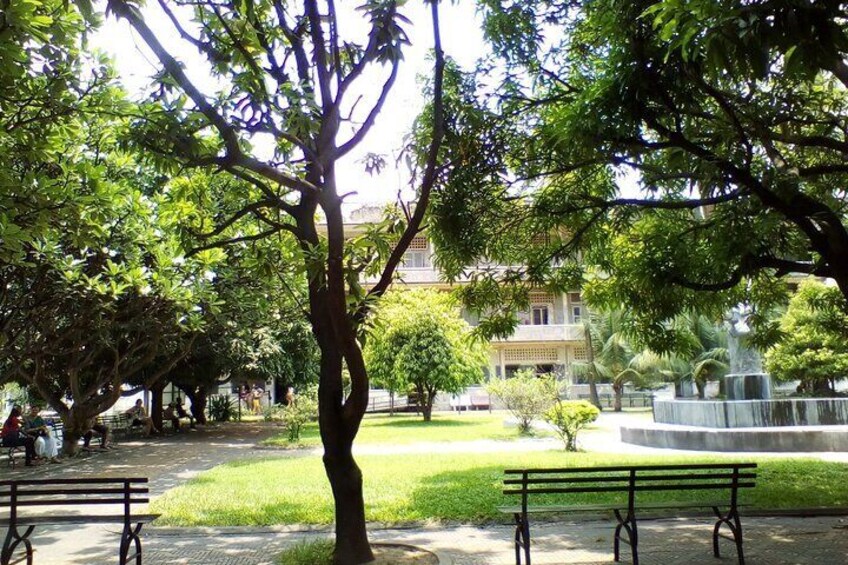 A park with a large tree, a fountain, and benches. 3
