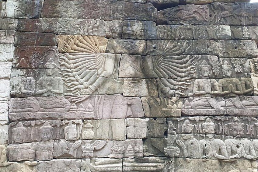 Un muro de piedra con intrincados grabados de figuras y diseños. 3