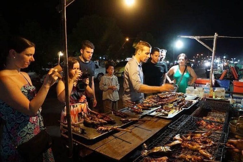 A nighttime outdoor barbecue with people grilling and socializing. 1