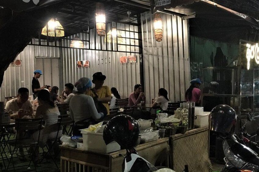 A bustling street food market with people dining and vendors preparing food. 2