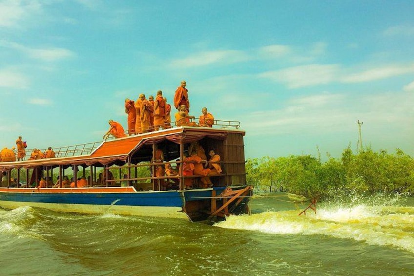 A boat with people wearing orange robes, moving through a river. 5