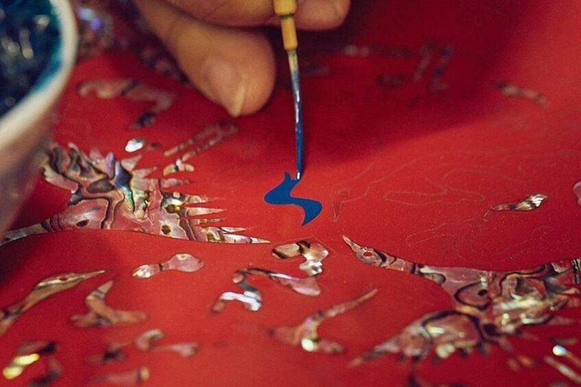 Una mano pintando sobre una superficie roja con un pincel azul. 5