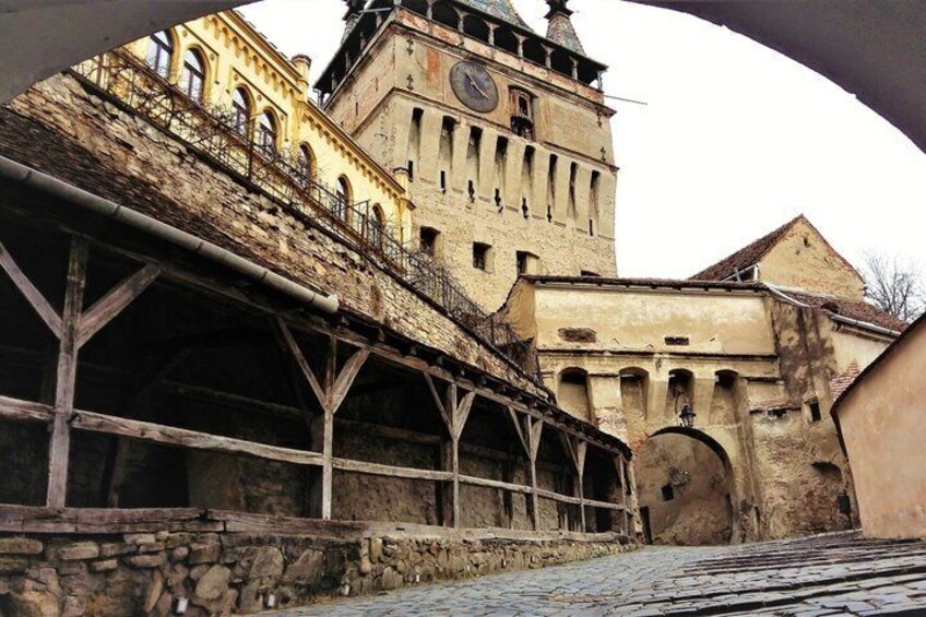 A historic building with a clock tower, a covered walkway, and stone walls. 3