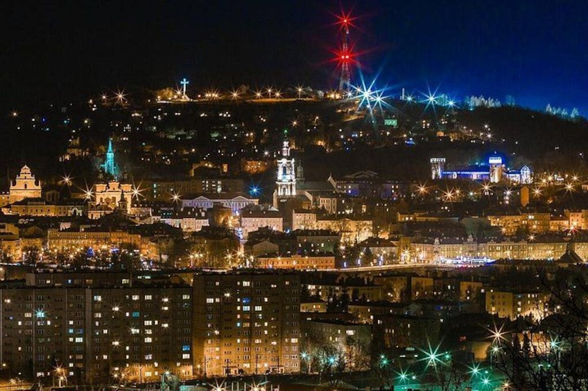 A cityscape at night with illuminated buildings and a hilltop structure. 2