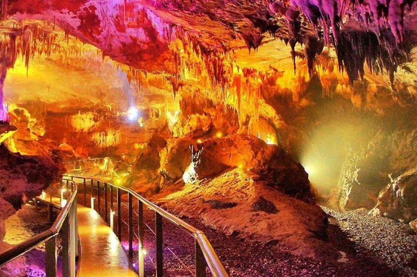 Una cueva con estalactitas iluminadas y un pasillo. 2