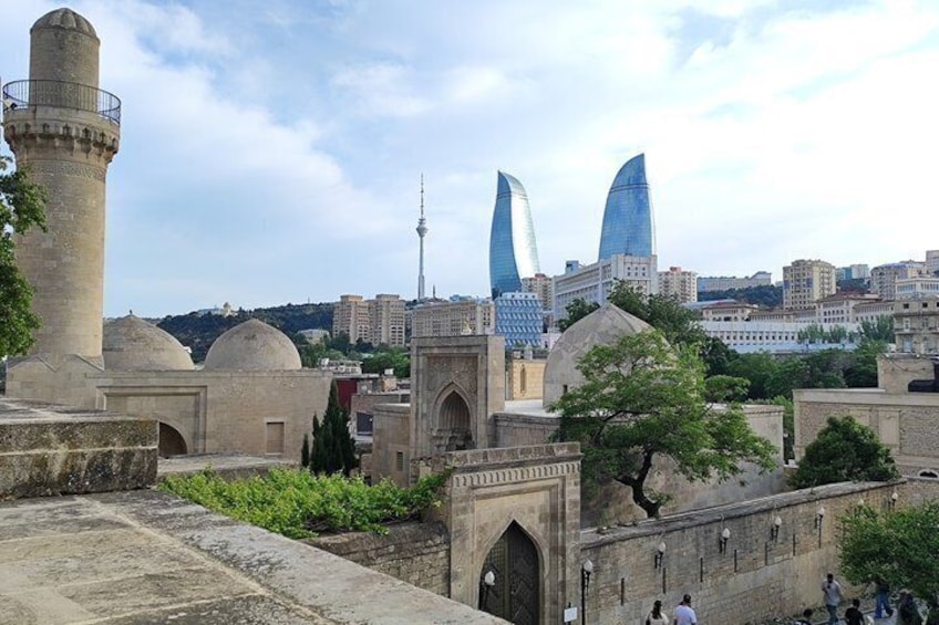 Una mezquita histórica con un minarete, arquitectura tradicional y un moderno paisaje urbano con rascacielos al fondo. 5